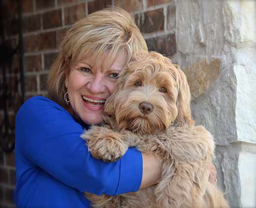 Lady wearing a blue dress holding an Australian Labradoodle puppy